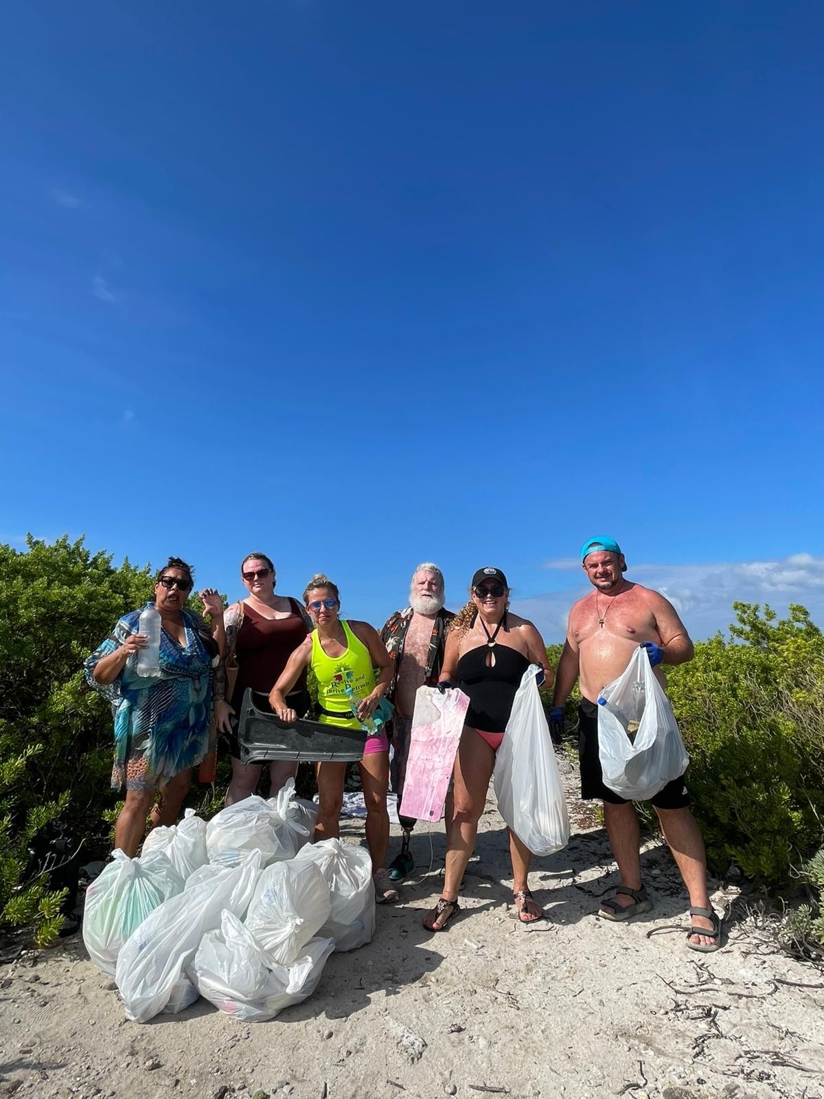 Beach cleanup team with collected trash bags